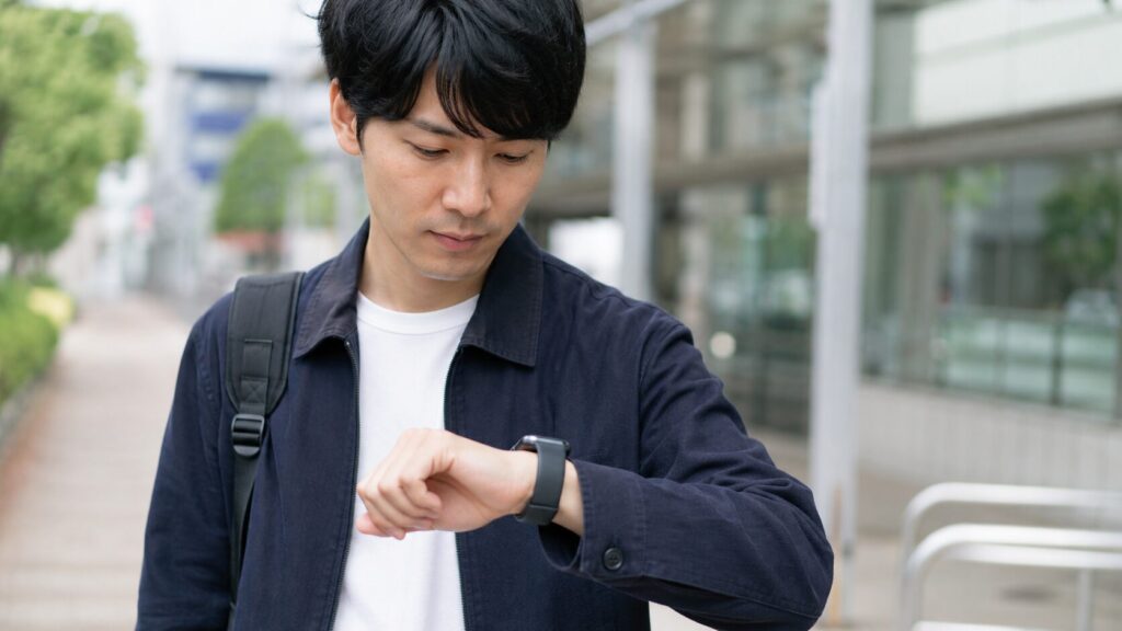 街中で手首に着けたアップルウォッチを確認する日本人男性